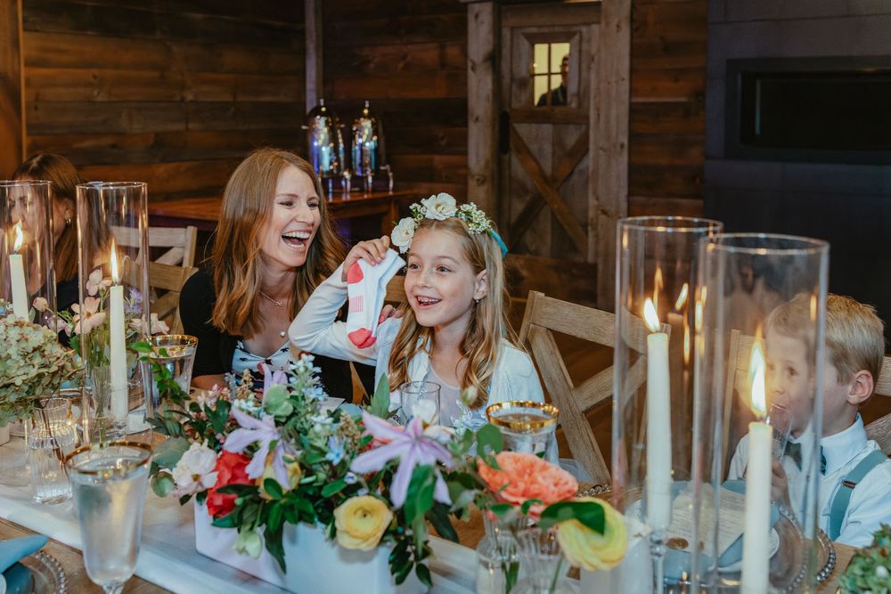 A candlelit reception table at a rustic wooden venue with elegant floral centerpieces and glowing ambiance.