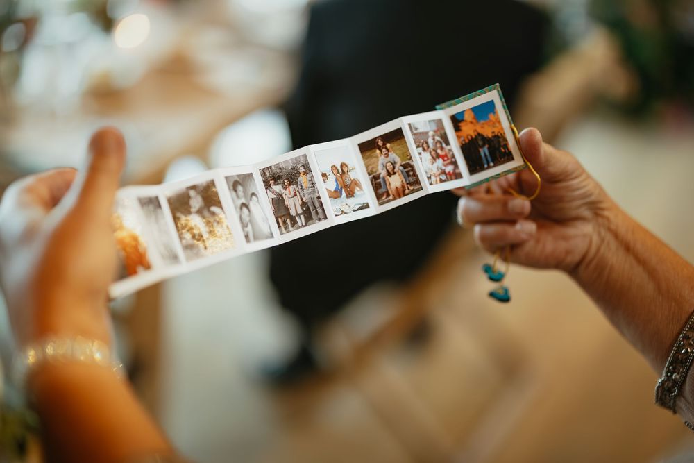 Hands holding a strip of photo booth pictures at a wedding reception.