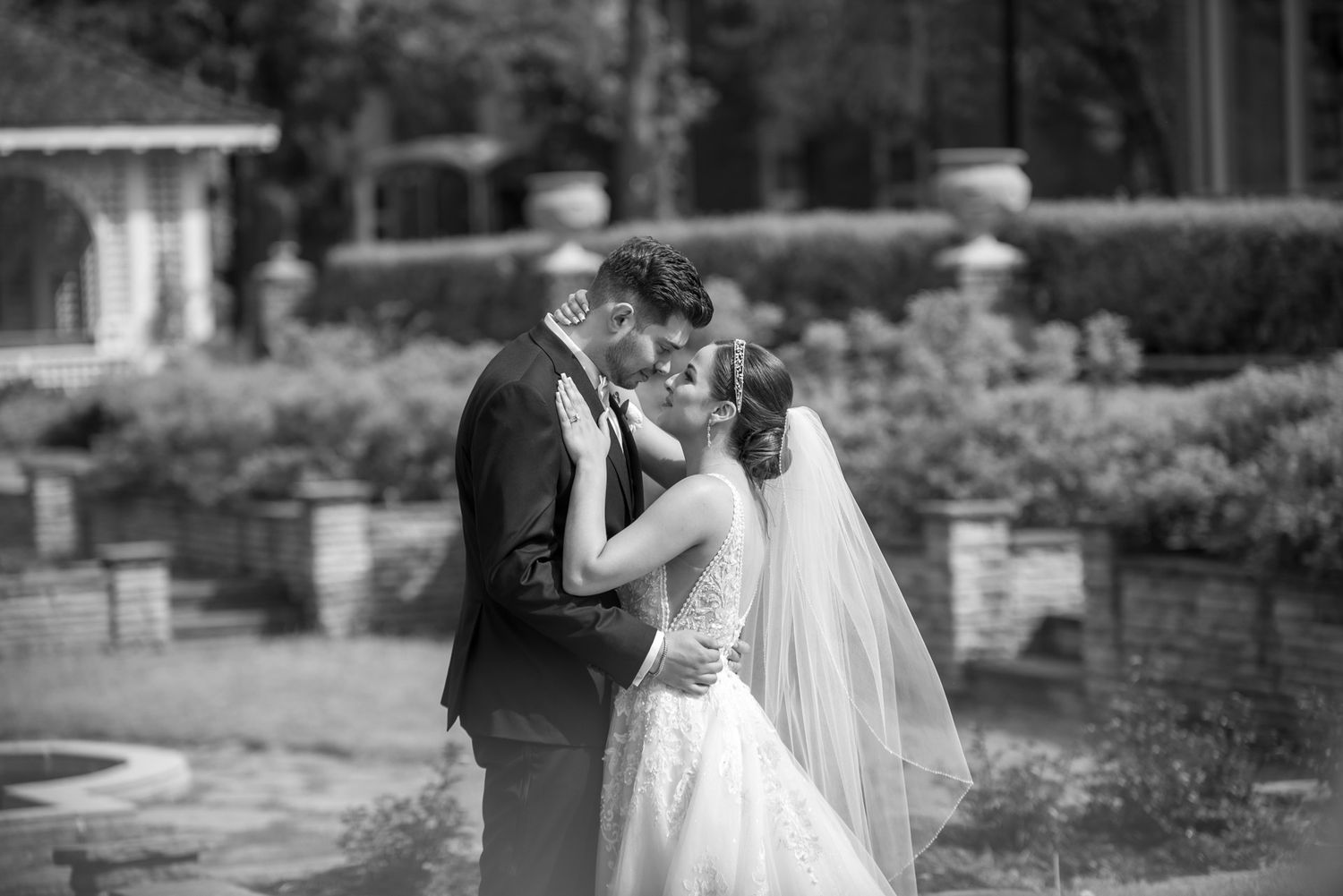 Bride and groom sharing a romantic kiss in black and white garden wedding photo at Glendon College Gardens