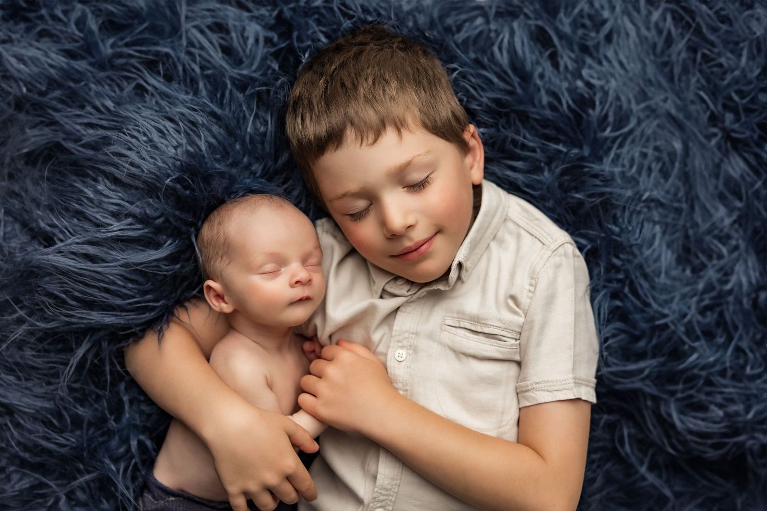 Peaceful sleeping newborn wrapped in cream-colored knit swaddle resting on yellow cushion.