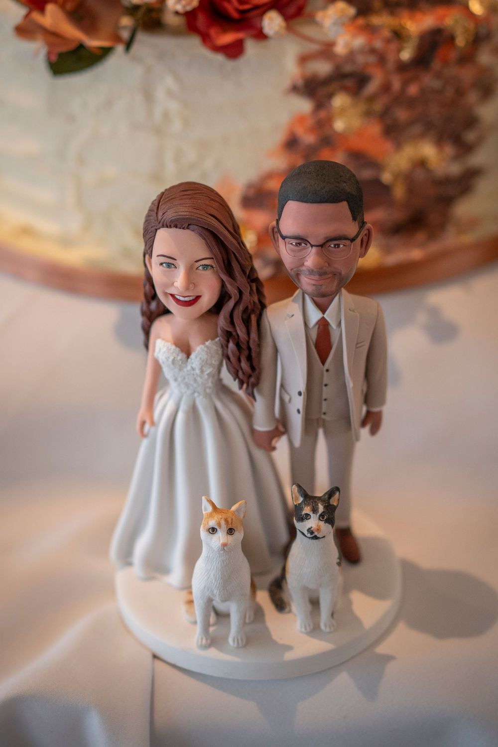 Custom wedding cake topper featuring miniature figures with two pet dogs in formal attire.