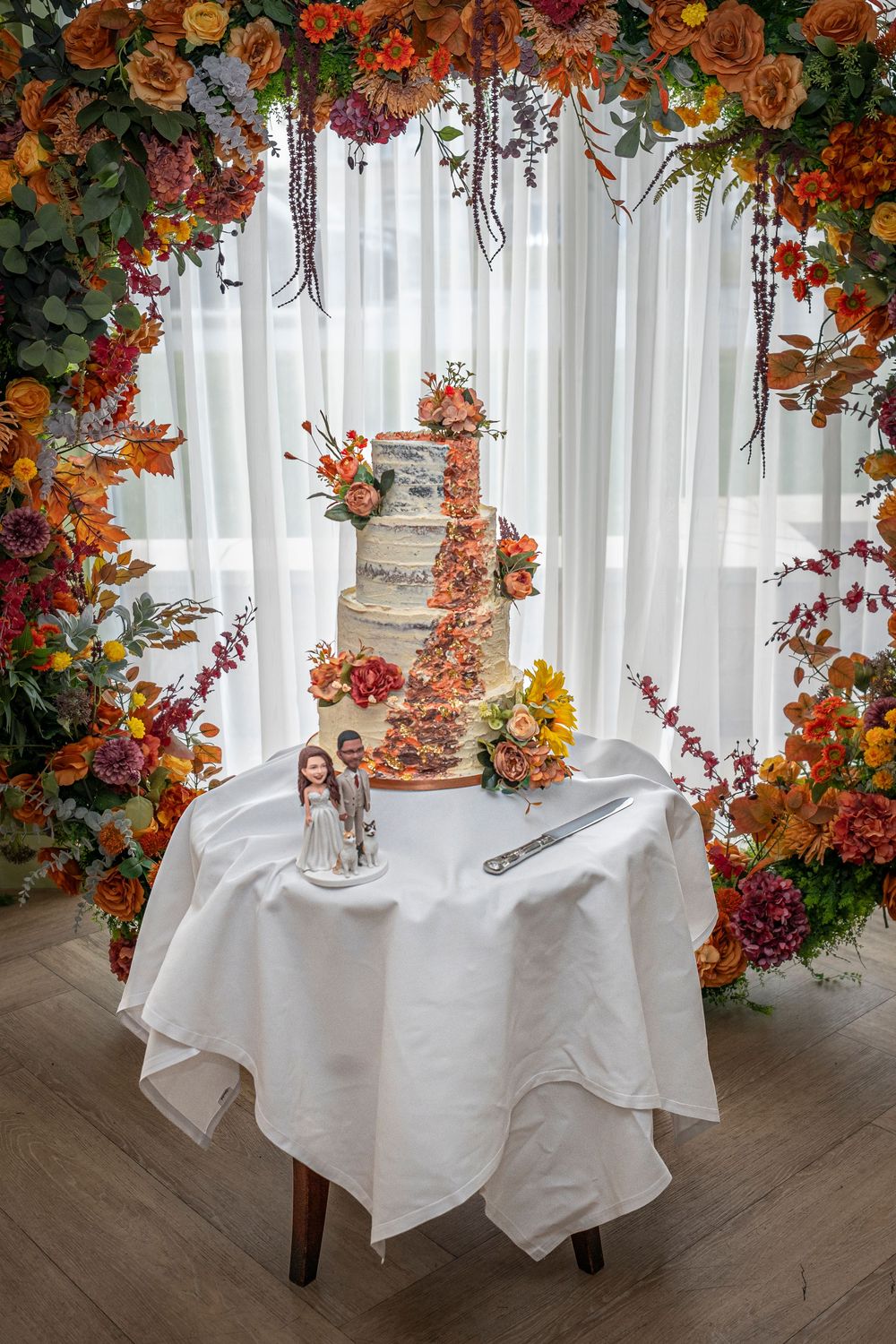 Wedding reception table with rustic decor and cascading autumn-colored floral arrangements.