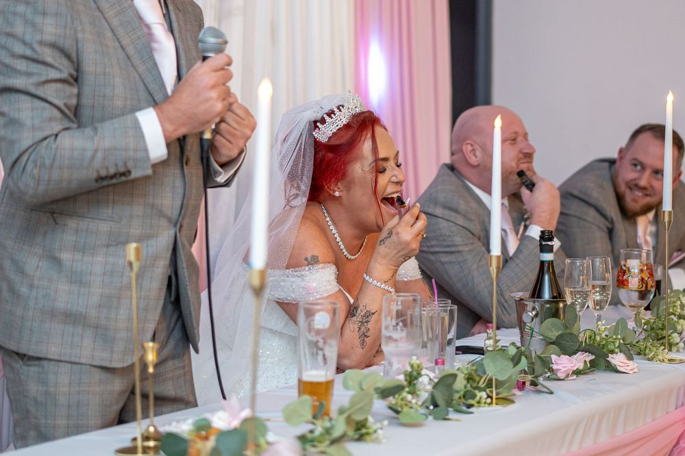 Wedding reception head table decorated with greenery and candles.