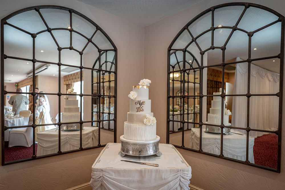 Modern wedding venue with geometric window panels and white wedding cake display.