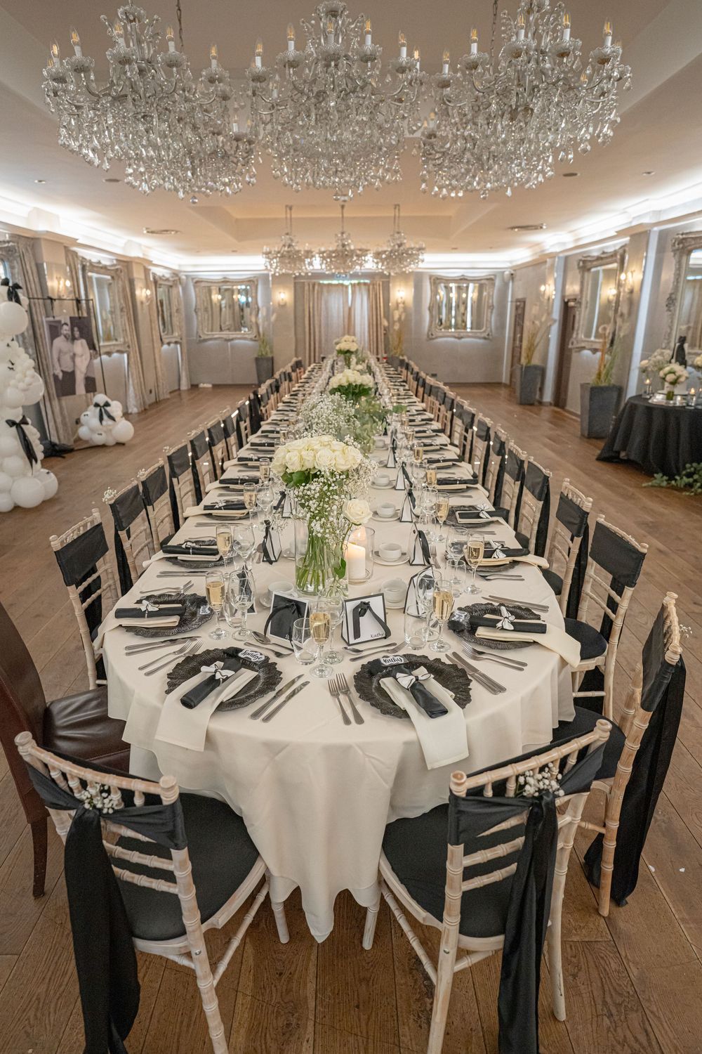 Formal wedding reception setup with crystal chandeliers and round tables set with white linens.