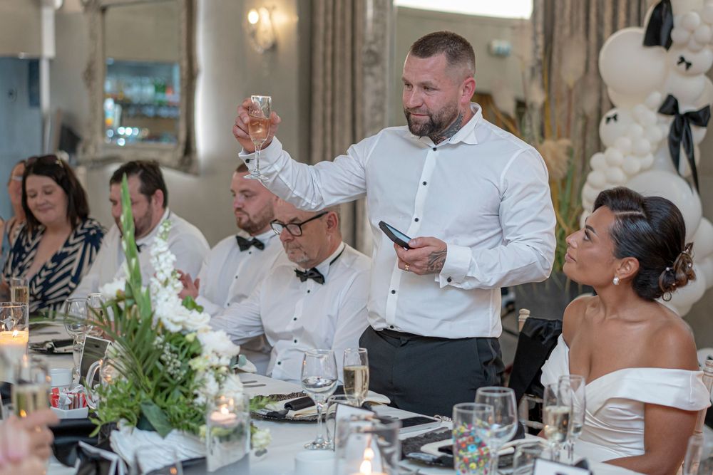Wedding reception guests enjoying a formal dinner celebration at elegantly set tables with white linens and floral centerpieces.