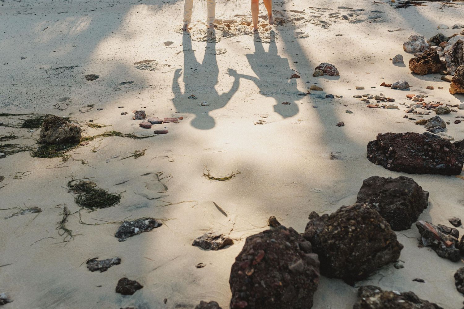 Creative engagement photo of couple shadows holding hands on the sand in Tróia