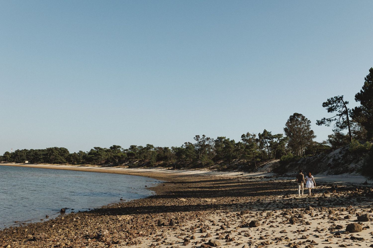 Wide beach view with couple walking in the distance during engagement shoot in Setúbal