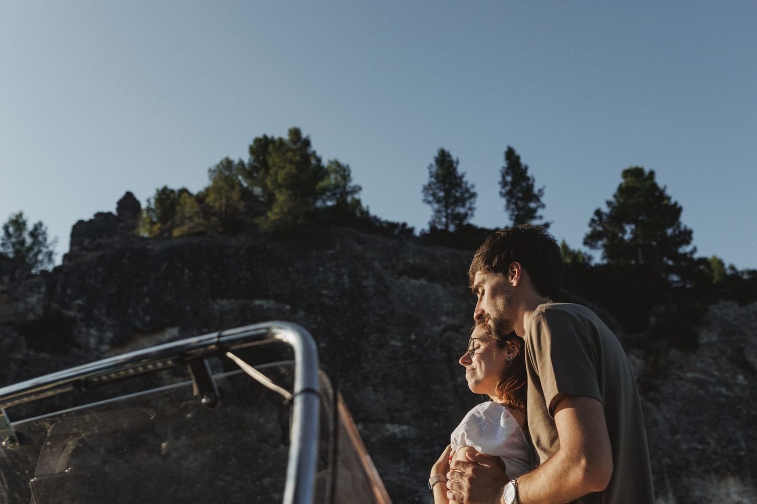 Romantic engagement moment of couple embracing on a boat in Tróia at golden hour