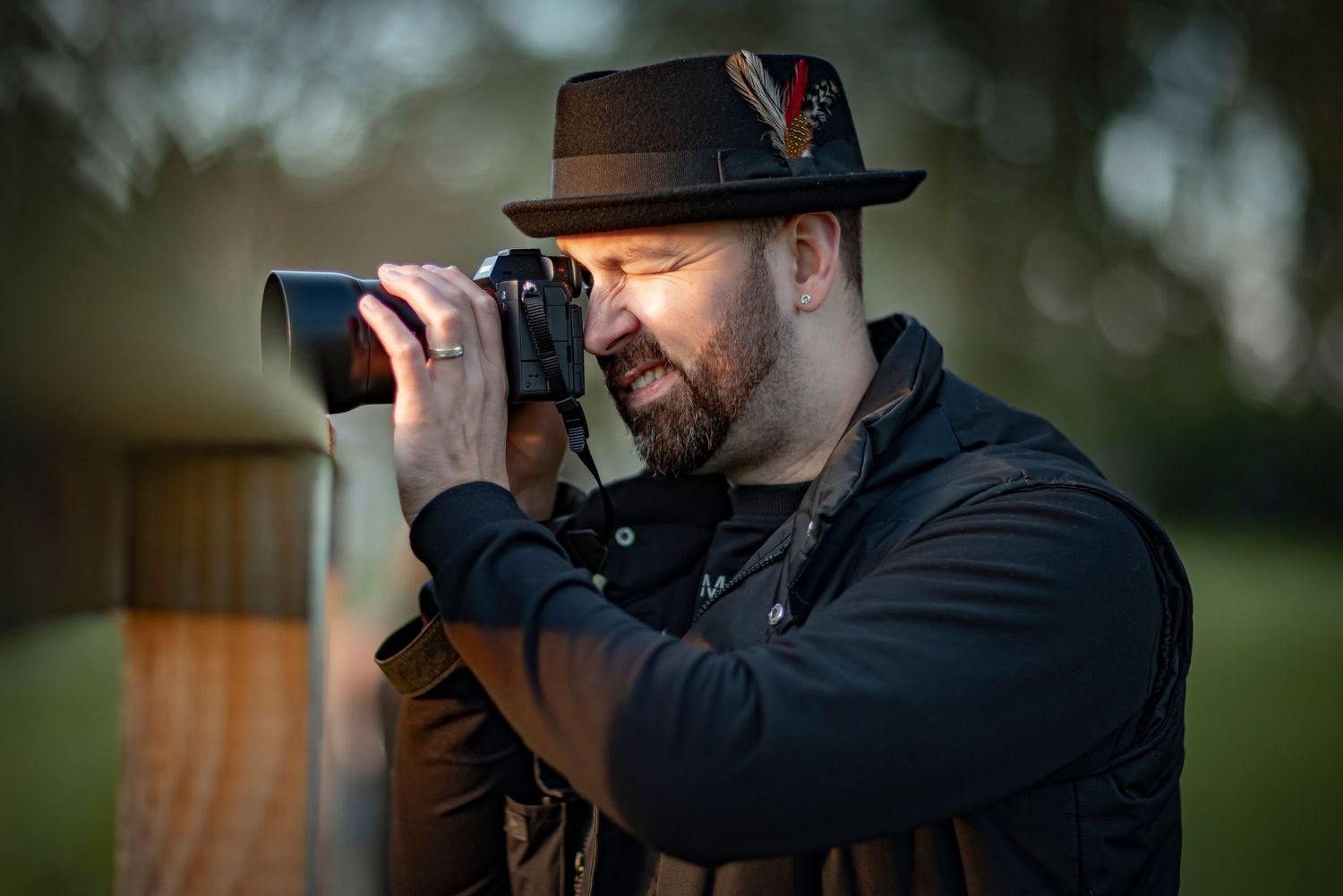 Professional photographer in hat using camera during outdoor photo session.