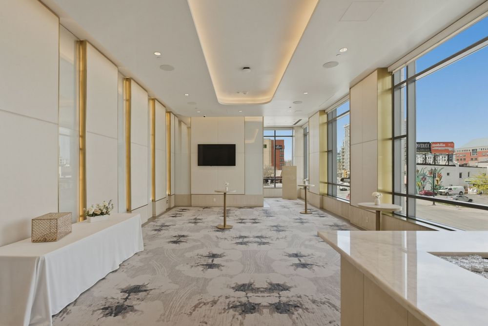 Modern office hallway with recessed lighting, marble floors, and floor-to-ceiling windows offering city views.
