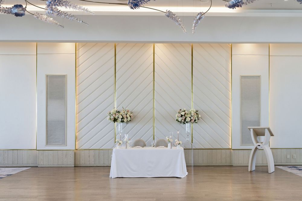 Modern white event space with diagonal wall panels and chandeliers creates an elegant minimalist atmosphere.
