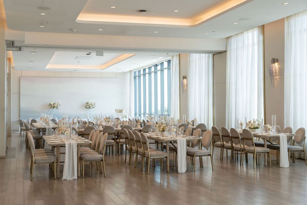 Elegant banquet hall with white tablecloths, modern lighting, and floor-to-ceiling windows offering panoramic views.