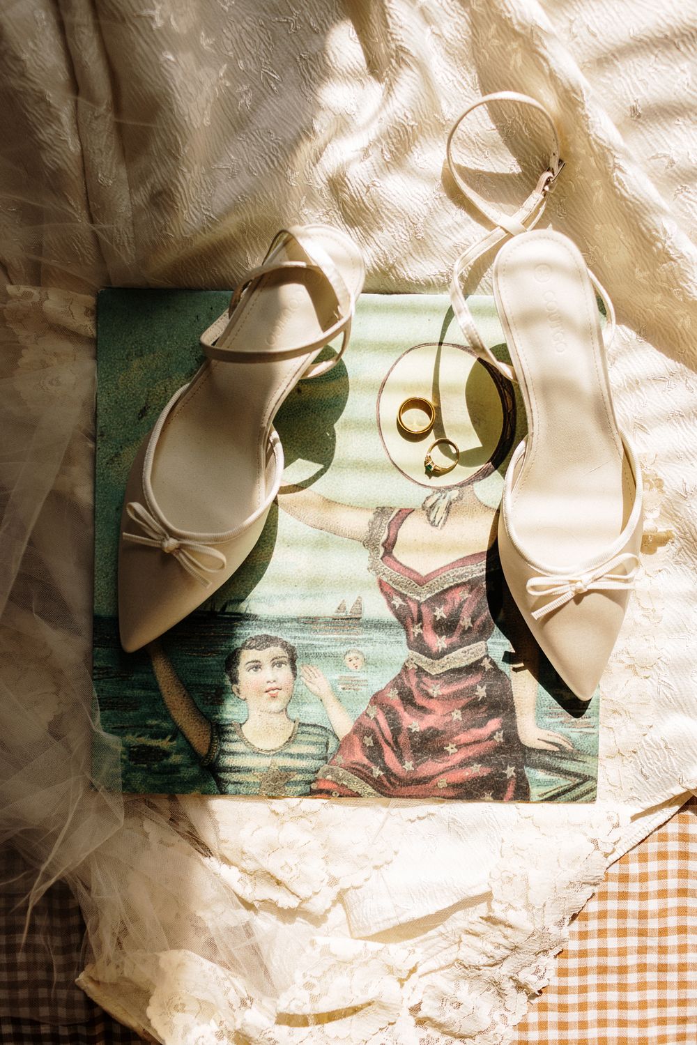 Sunlight on a vintage vinyl record with a veil, wedding shoes, and rings on it. North Shore MA Seacoast NH wedding photographer
