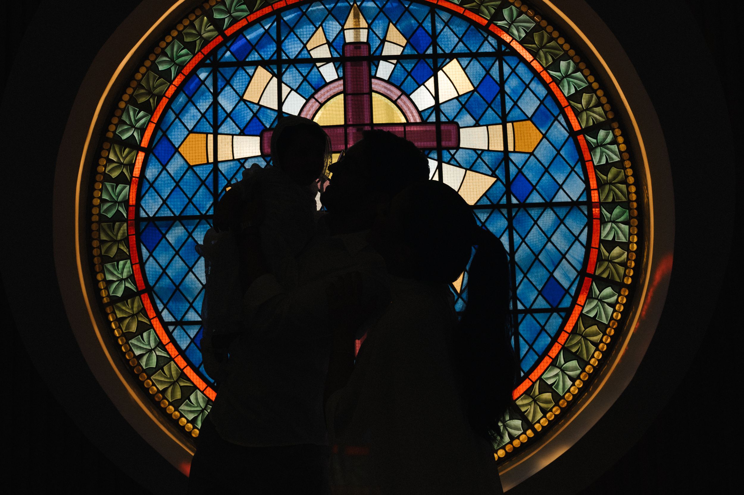 A series of stained glass church windows with ornate geometric patterns and blue tinted glass panels arranged in a row.