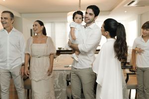 A group of people dressed in white and gray attire gather together in an indoor celebration setting.
