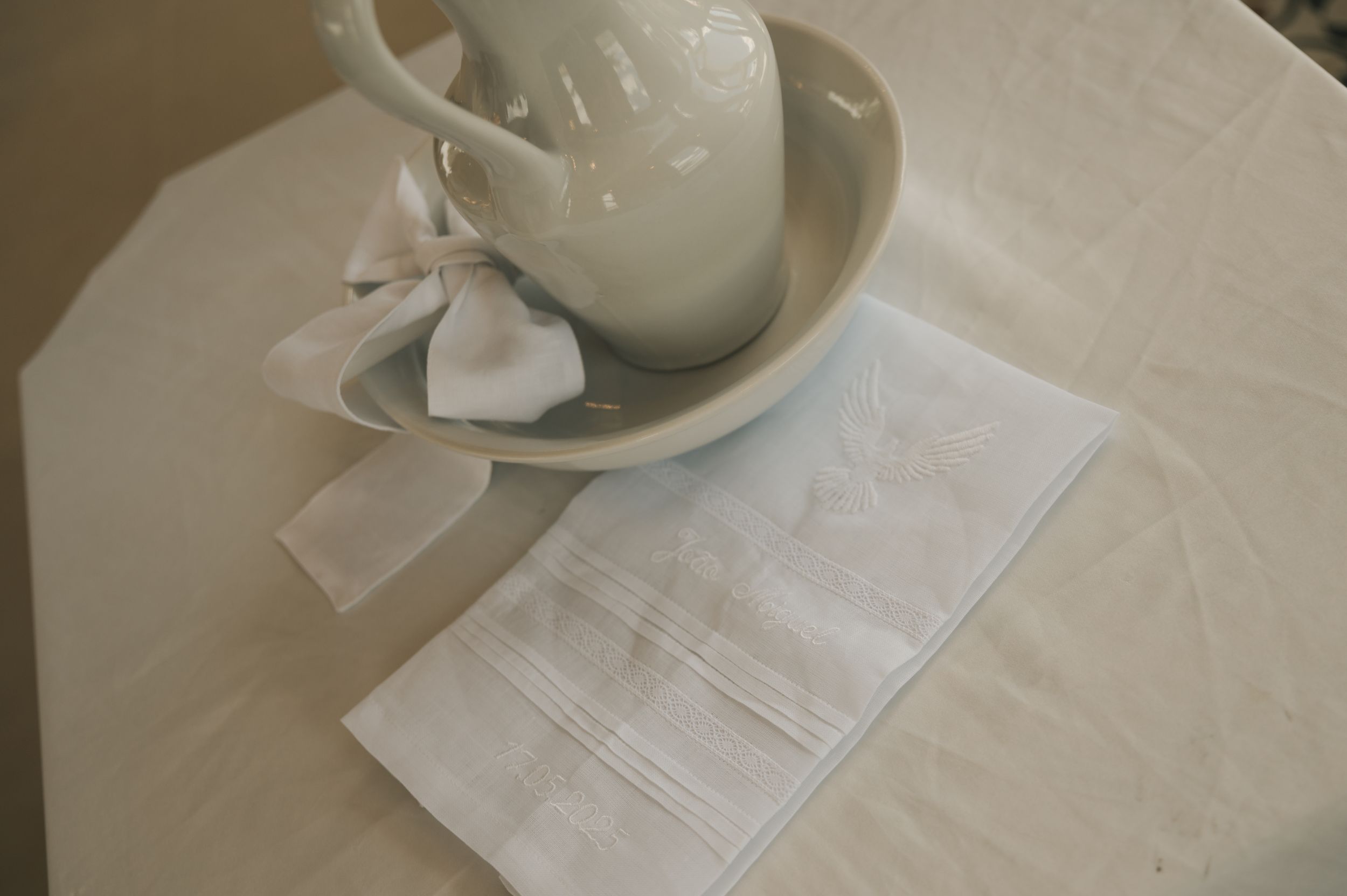 White ceramic teapot and cup set arranged on beige linen napkins on a light colored surface.