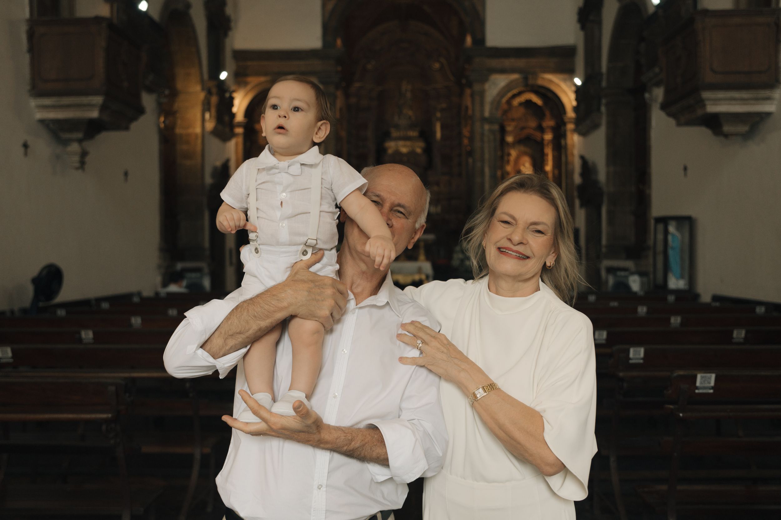 A collection of five black and white photos showing joyful moments between a parent and child in white clothing.