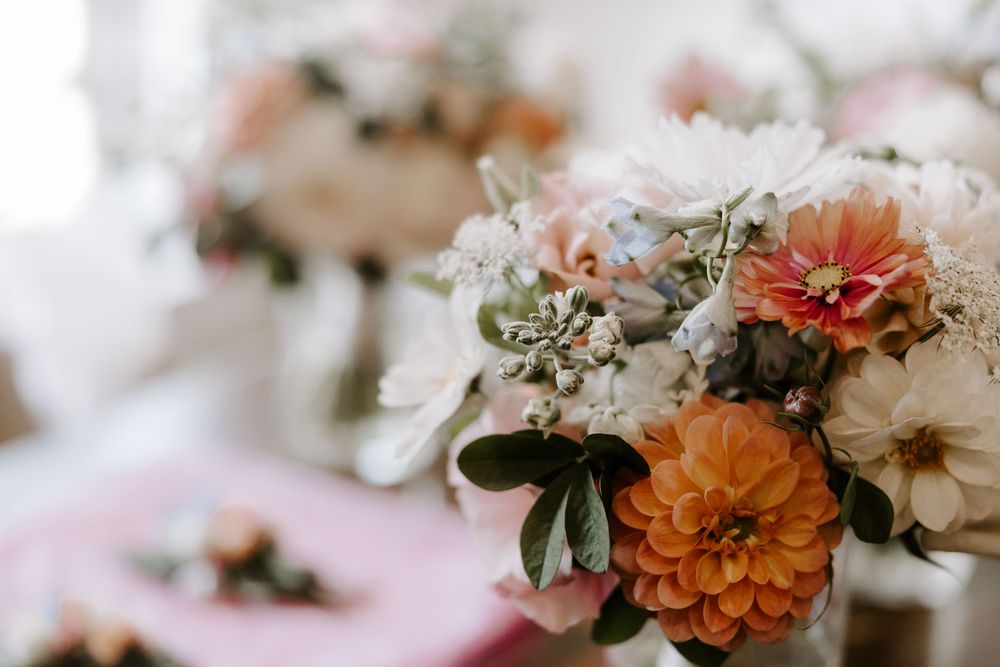Beautiful wedding centerpiece featuring orange dahlias, pink and white flowers in elegant arrangement.