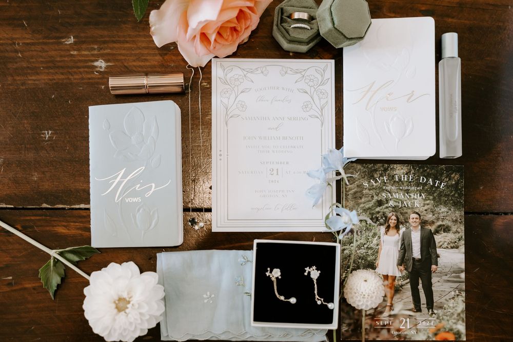 Elegant wedding stationery flat lay with invitations, save the date, earrings, and floral accents.