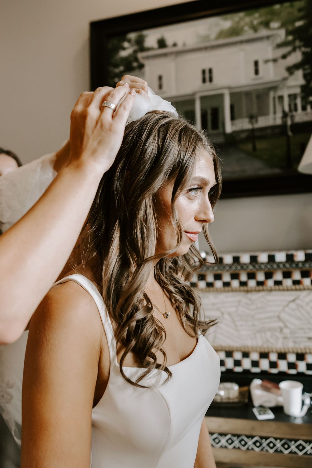 Bride getting veil placed in her hair while getting ready for her wedding day.