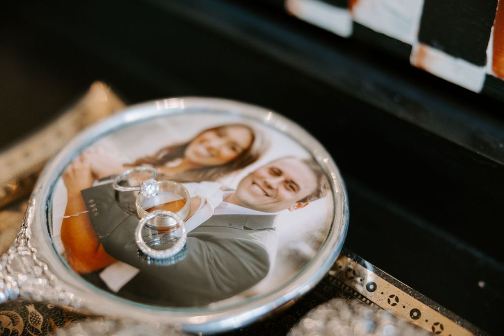 Wedding rings displayed on decorative silver tray featuring couple engagement photo as keepsake.