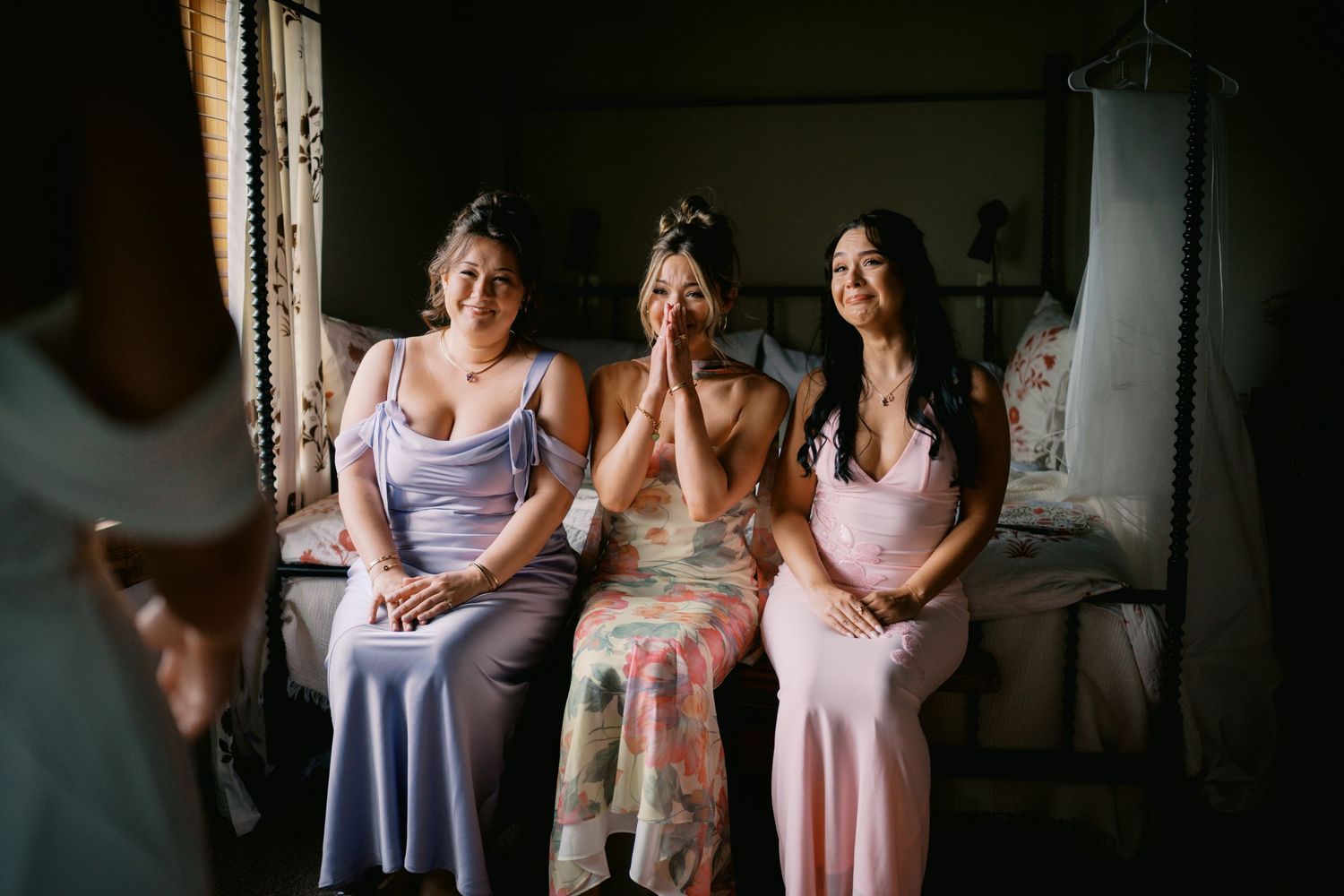 Three women in pastel dresses sitting together in a dimly lit room.