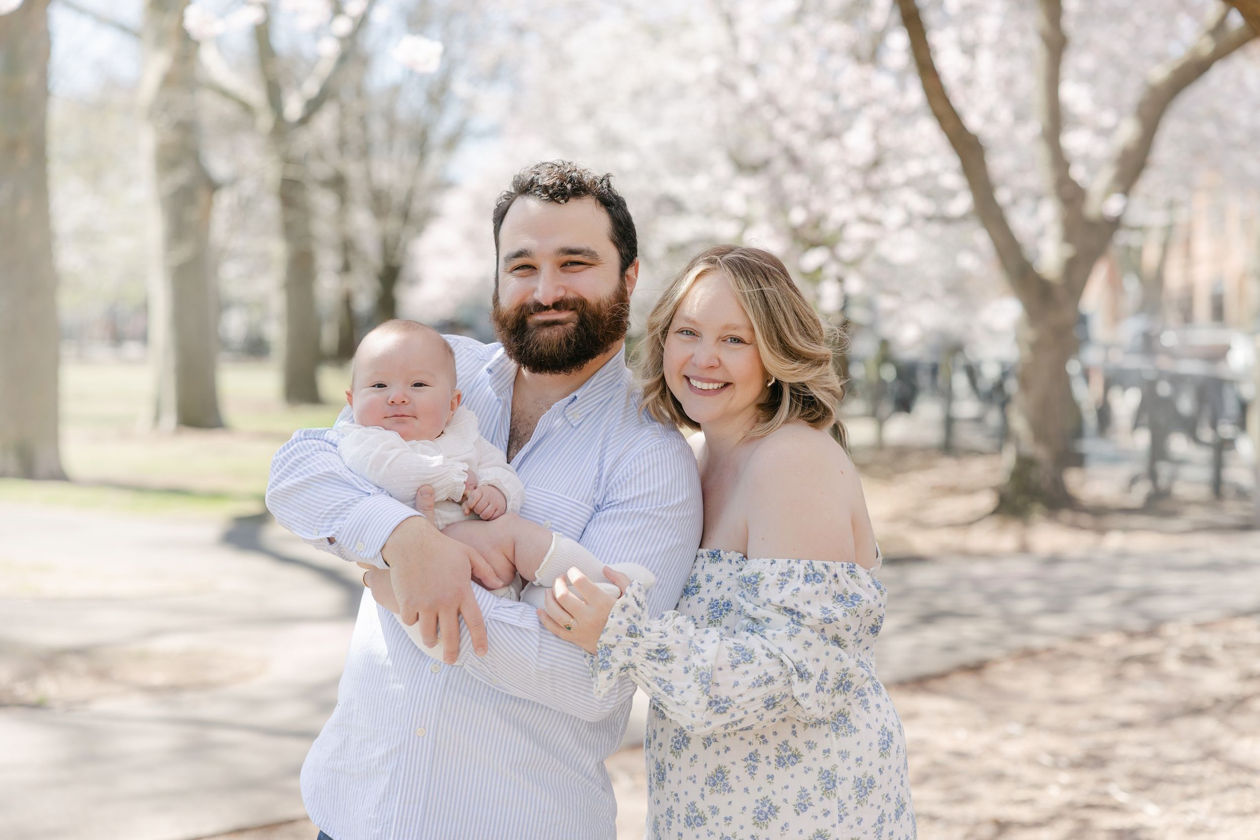 A family enjoys a sunny spring day together outdoors among blooming cherry blossom trees.