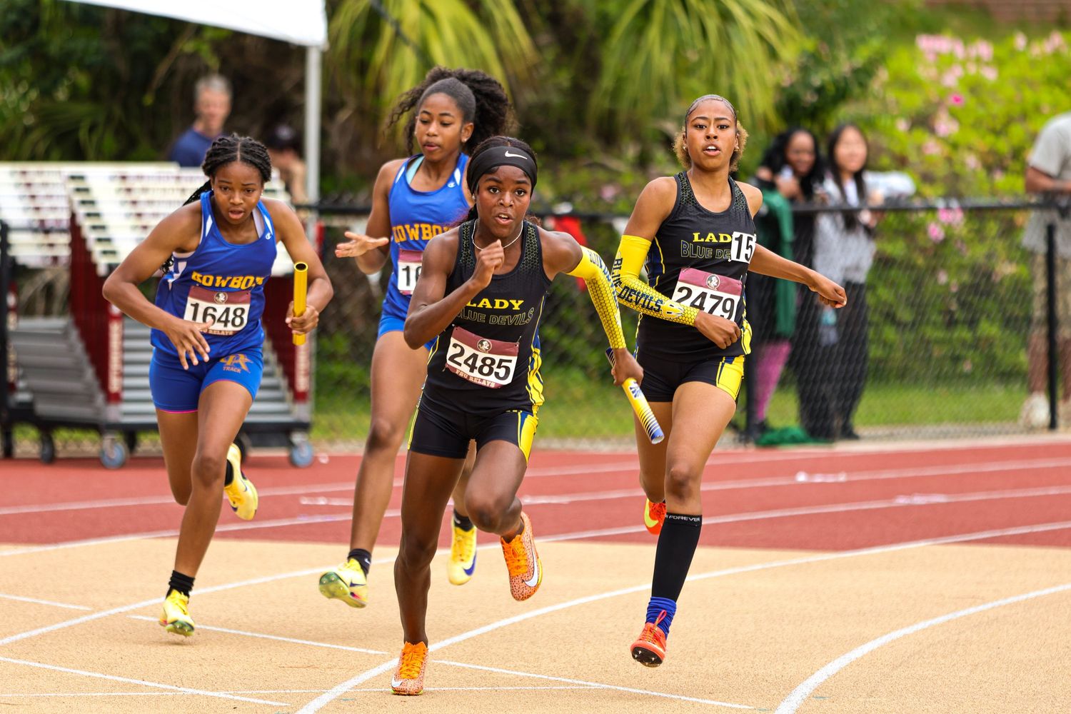 Track athlete clearing hurdles in sequence on outdoor running track during training session.