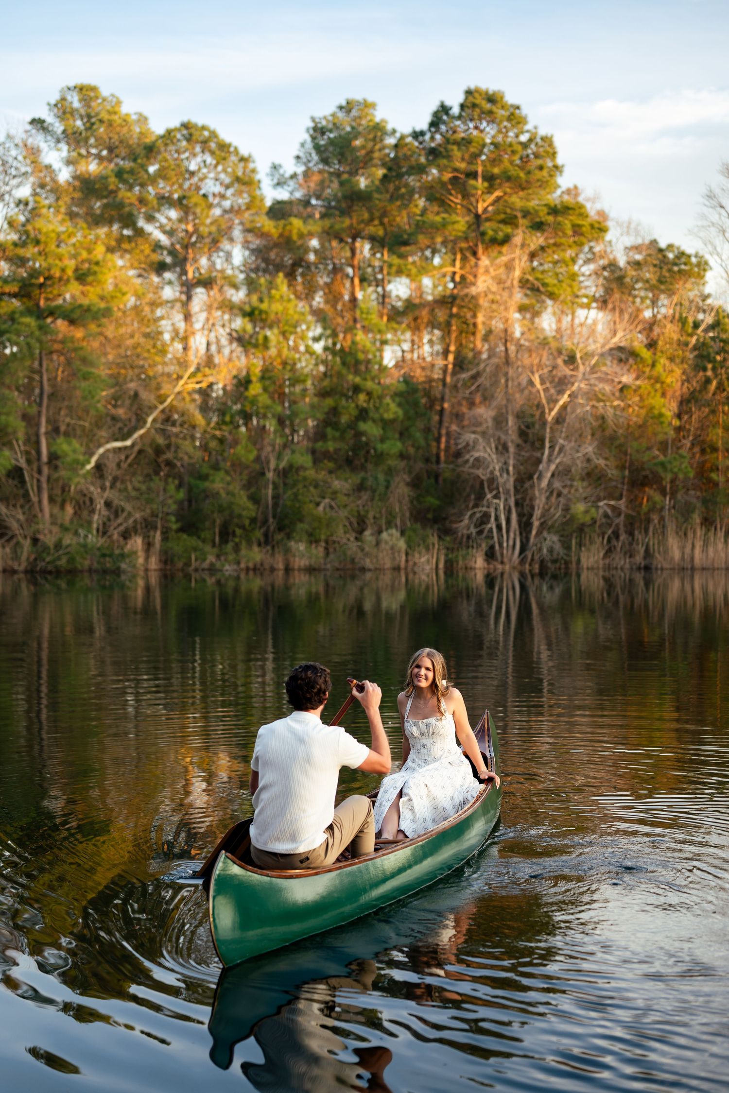 A couple enjoys a peaceful canoe ride through a cypress swamp during golden hour as sunlight filters through the trees.