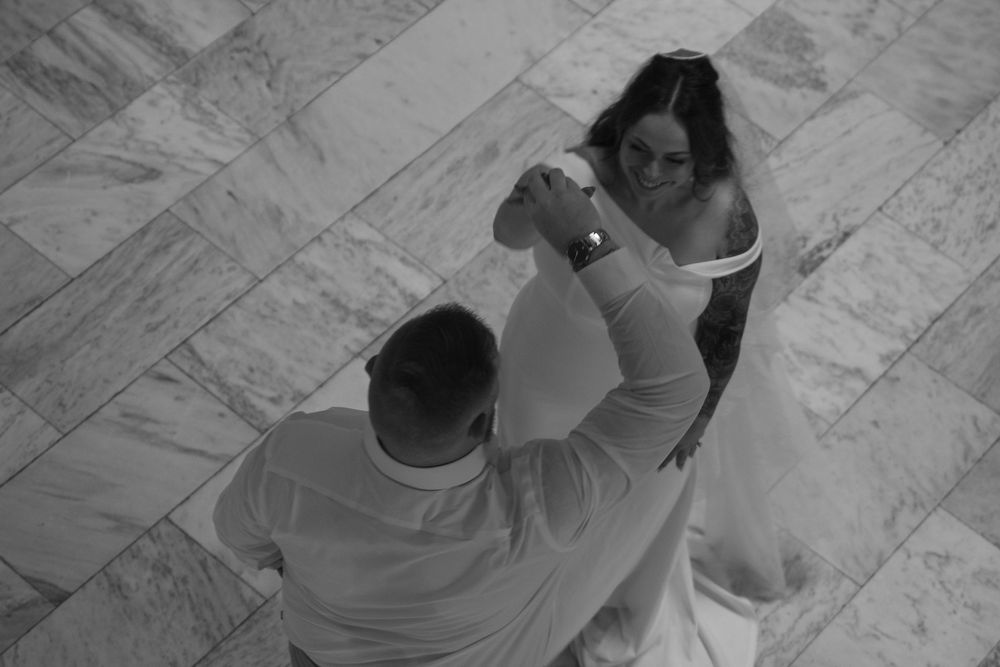 Black and white photo of a bride and groom sharing their first dance at a wedding reception.