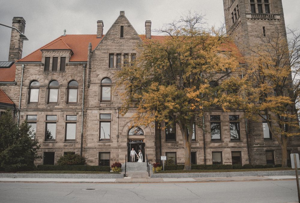 Historic stone university building with autumn trees and arched entrance, captured on an overcast day.
