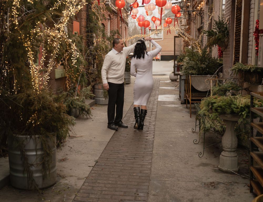 Couple dancing together in a charming alley adorned with red lanterns and twinkling fairy lights.
