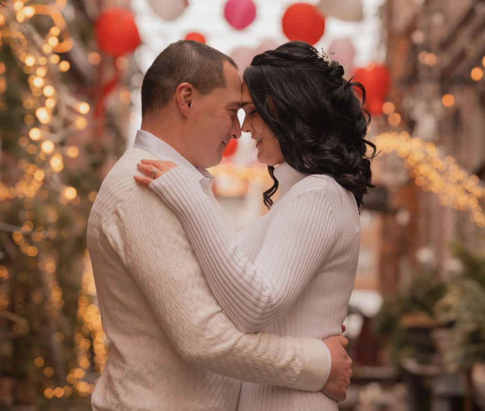 Romantic couple embracing in a festive outdoor setting with warm bokeh lights and red lanterns.
