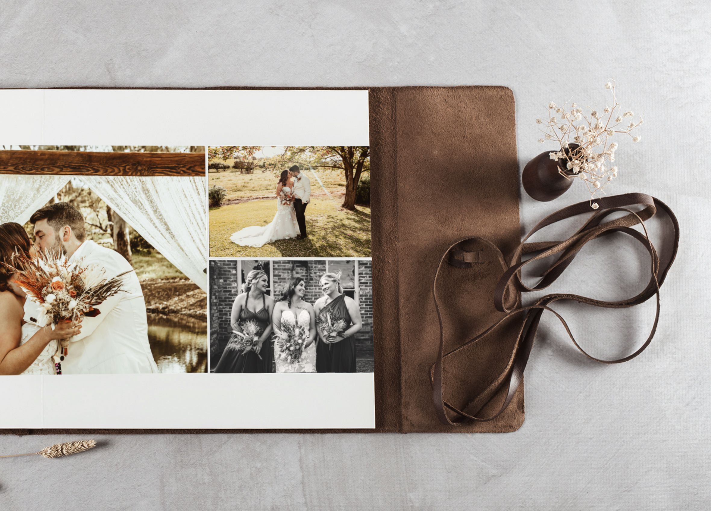 Rustic leather wedding photo album open displaying romantic couple and bridal party photos in warm tones.