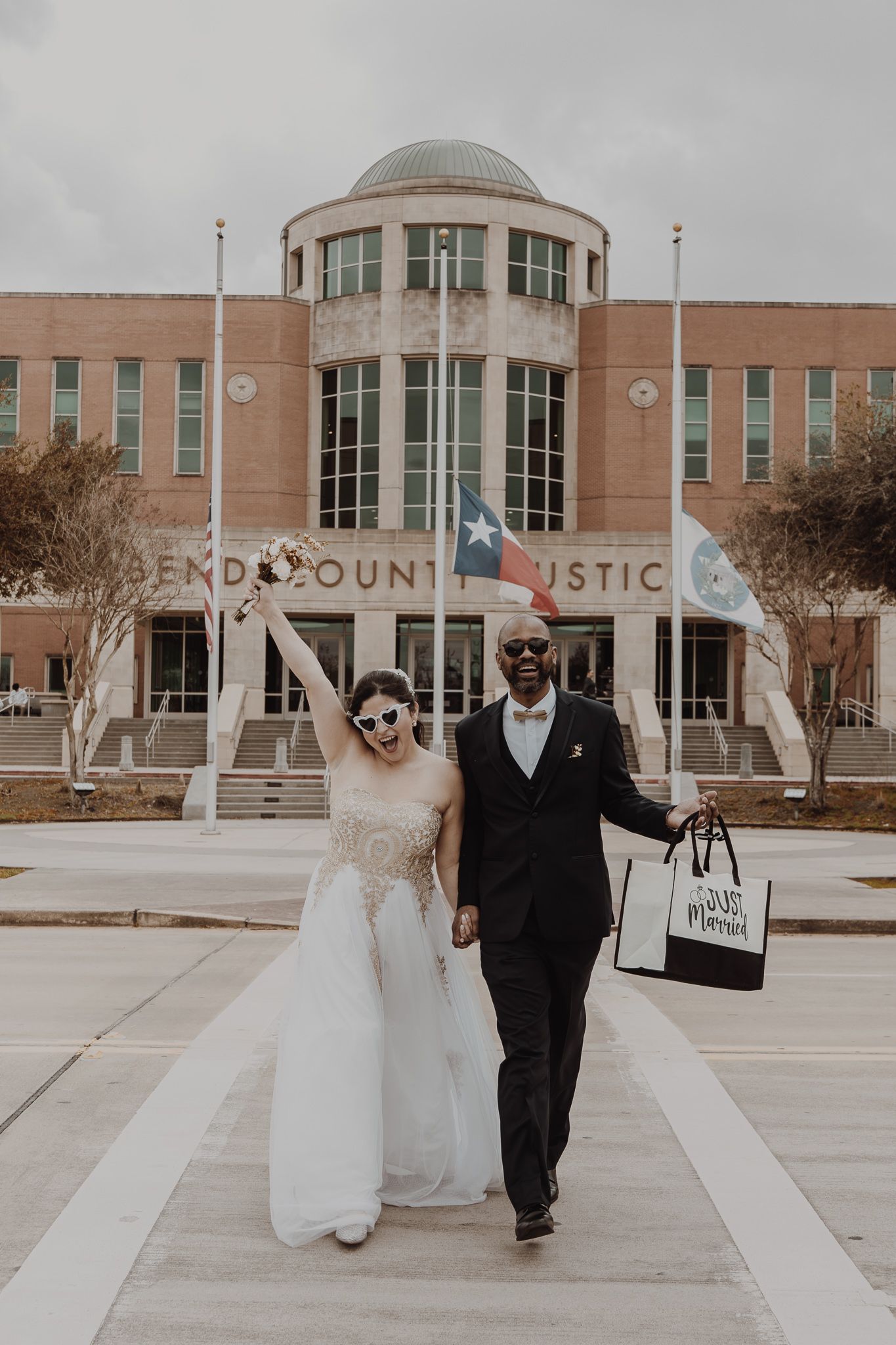 A couple exiting a grand building in formal attire on their wedding day.