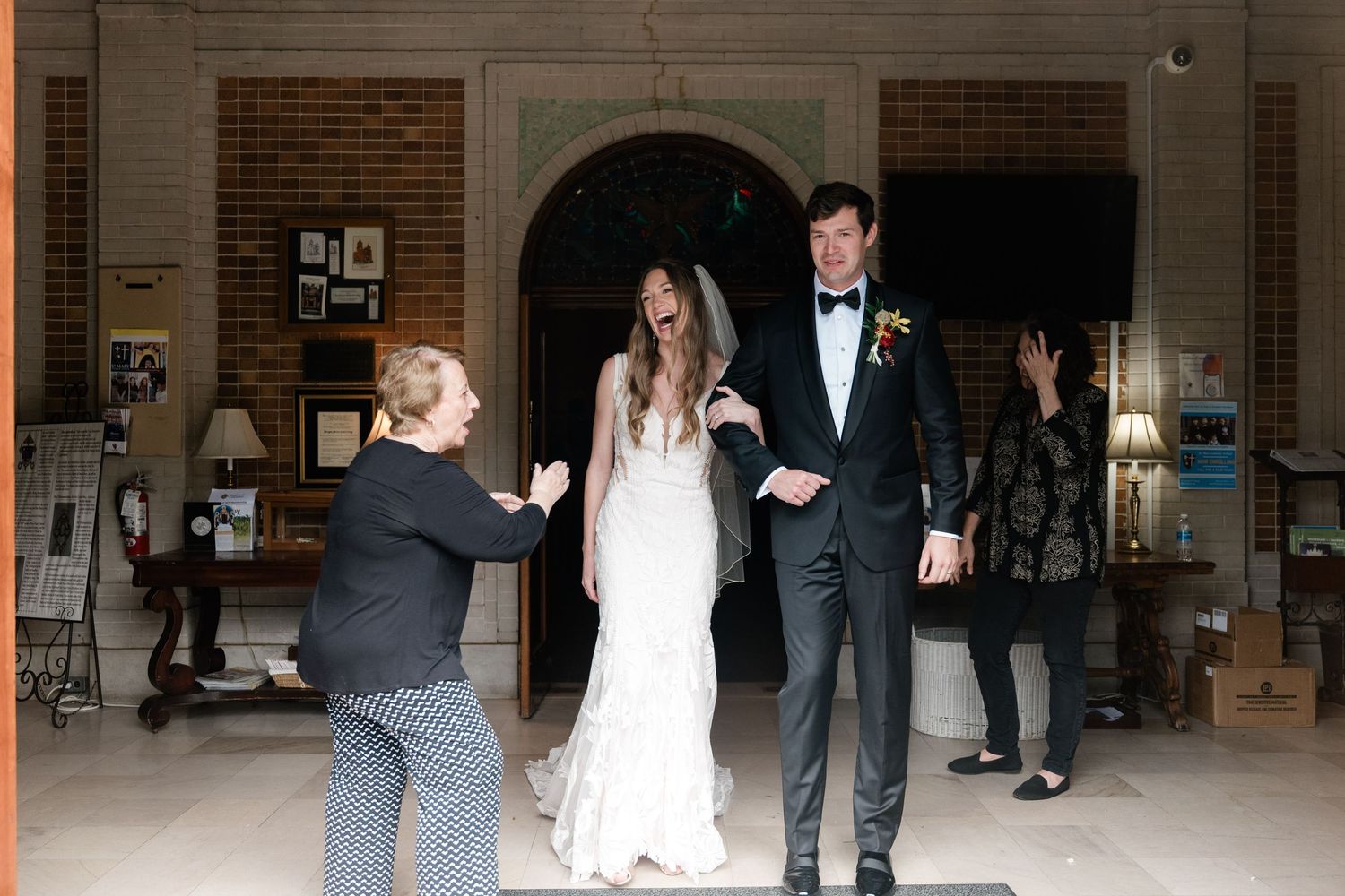 A couple exits through an arched doorway while being celebrated by guests at their wedding celebration.