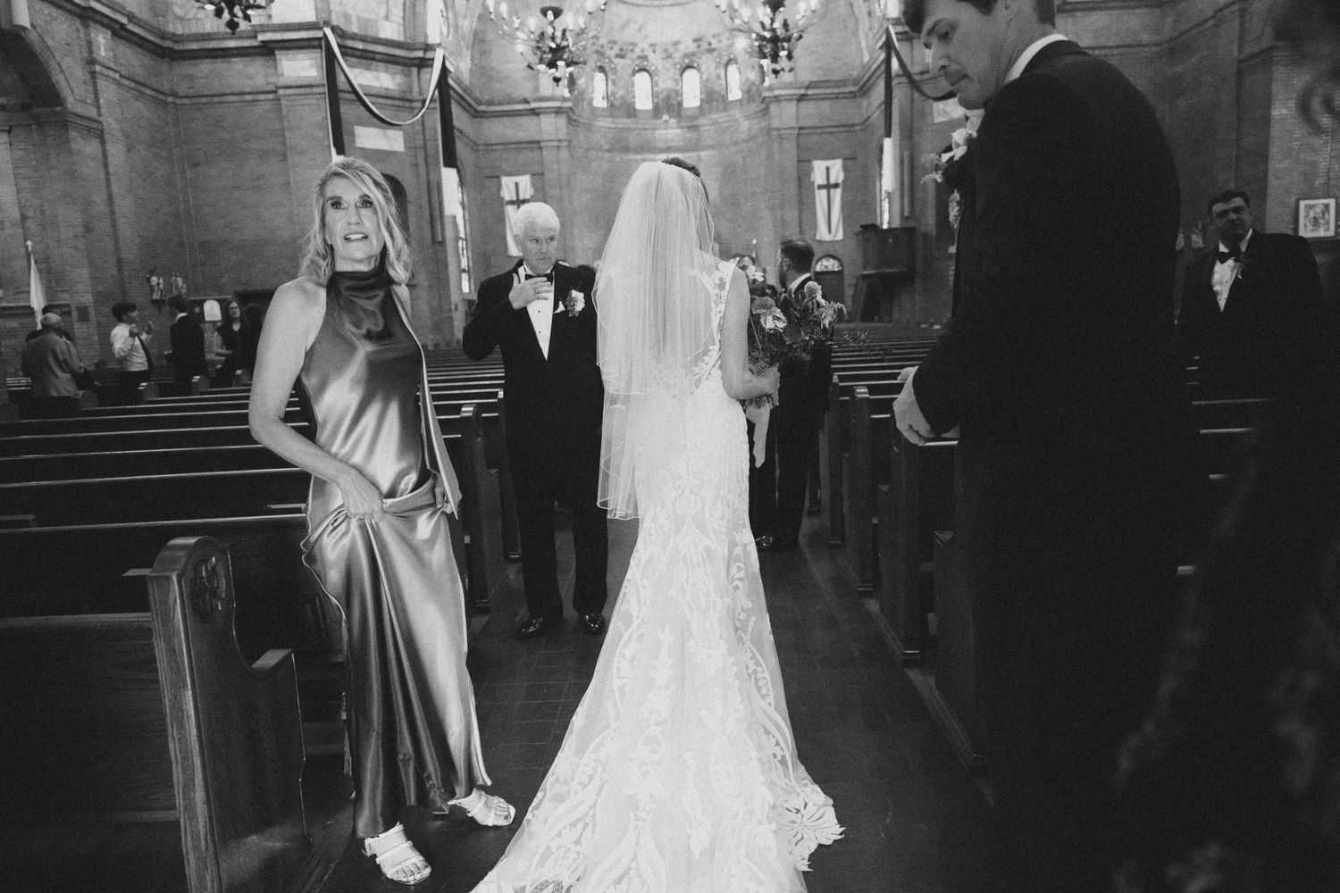 Wedding ceremony in progress inside grand church sanctuary with ornate architectural details.