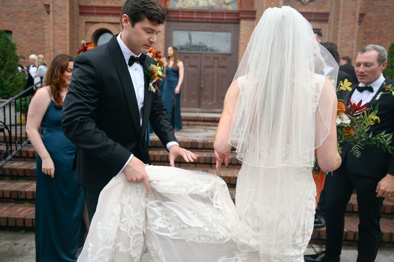 Wedding party members in formal attire walking across church entrance.