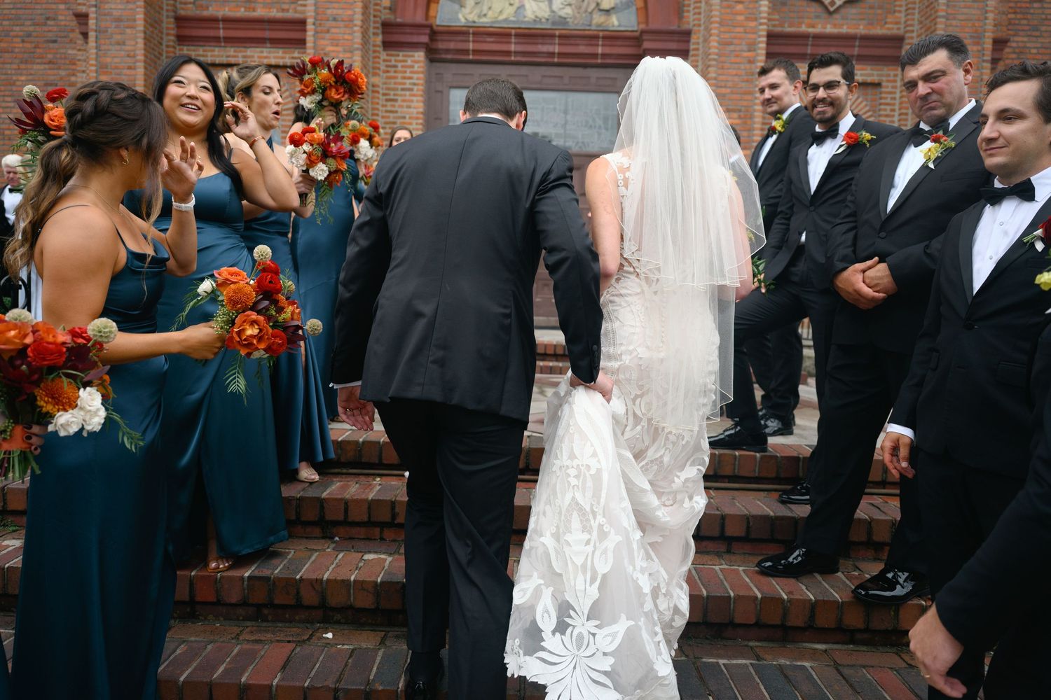Wedding celebration with navy and black attire outside historic brick church.