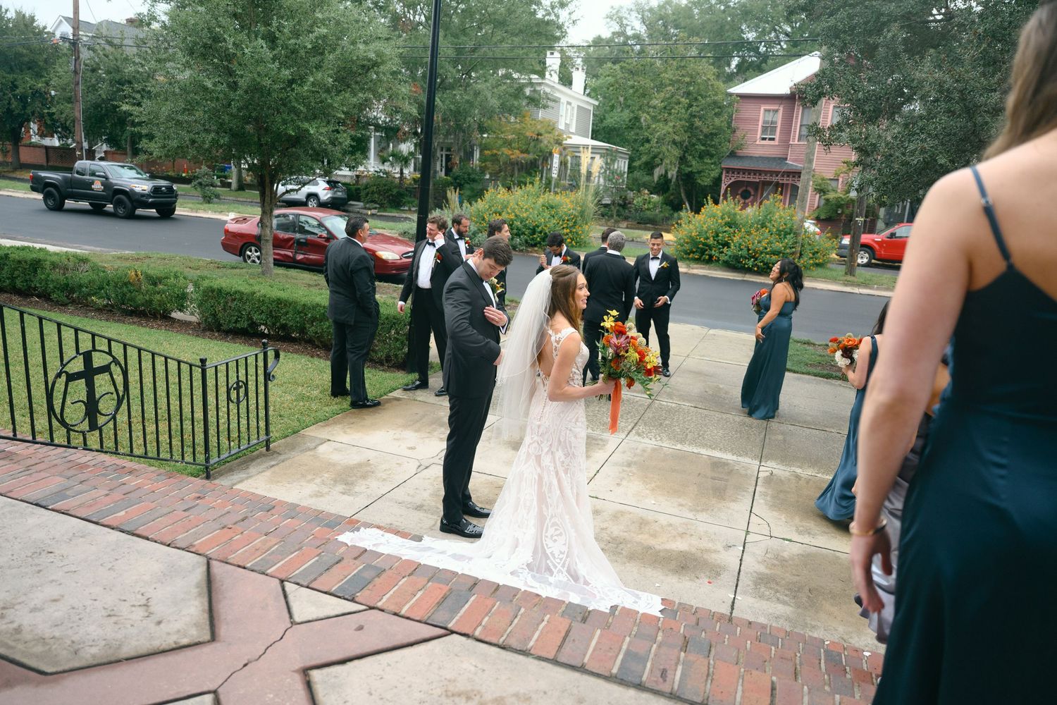 Wedding guests gathering outside historic brick building on city street.