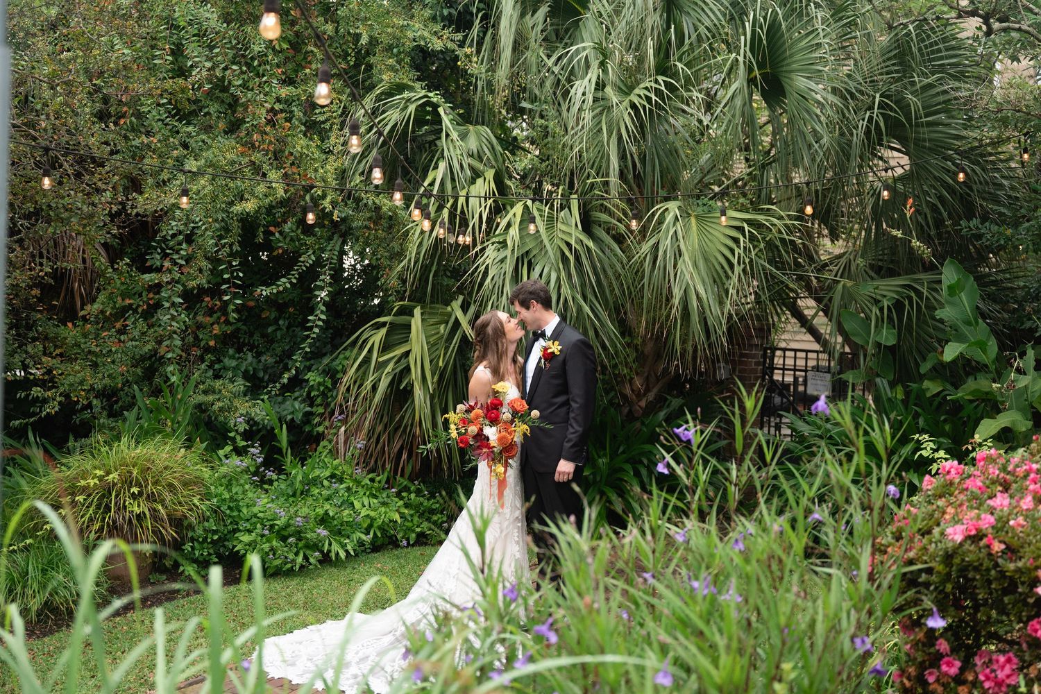 Wedding ceremony setting in a tropical garden with palm trees and colorful flowers.