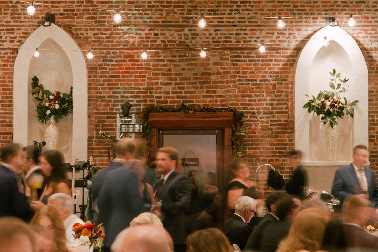 Wedding reception venue with exposed brick walls and string lights creating warm ambiance.