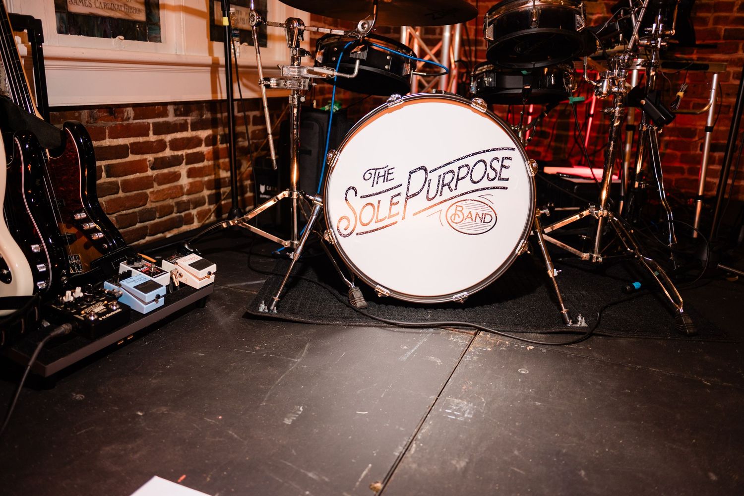 Rustic brick wall stage setup with musical instruments and equipment for a live performance.
