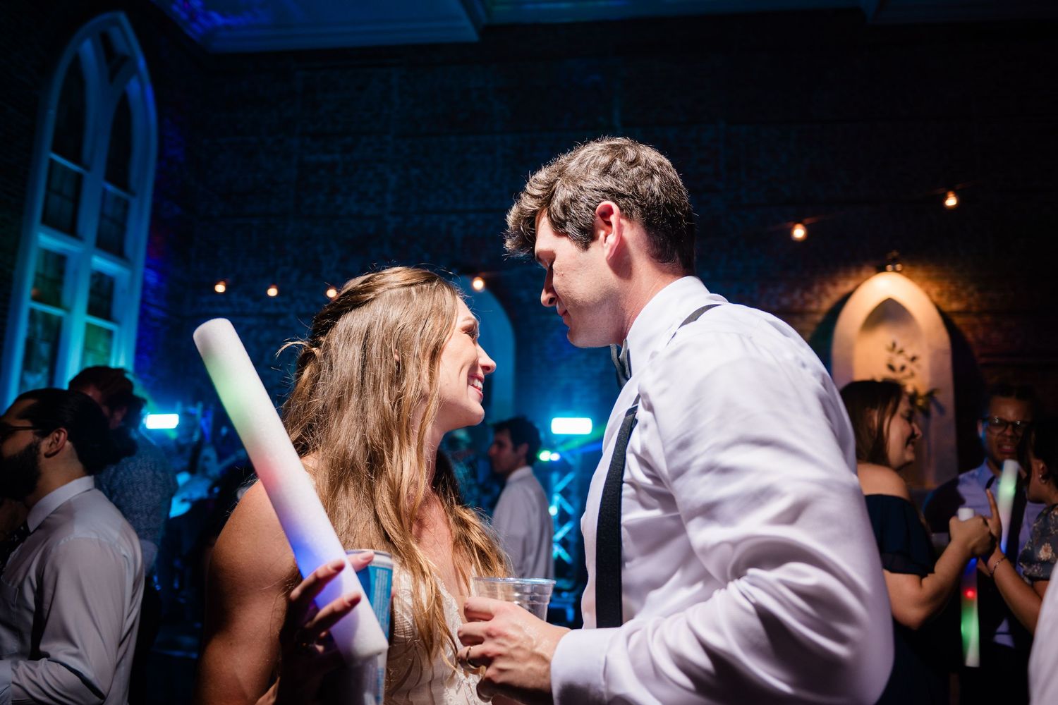 Couples dance together at an evening wedding reception with blue lighting and festive atmosphere.