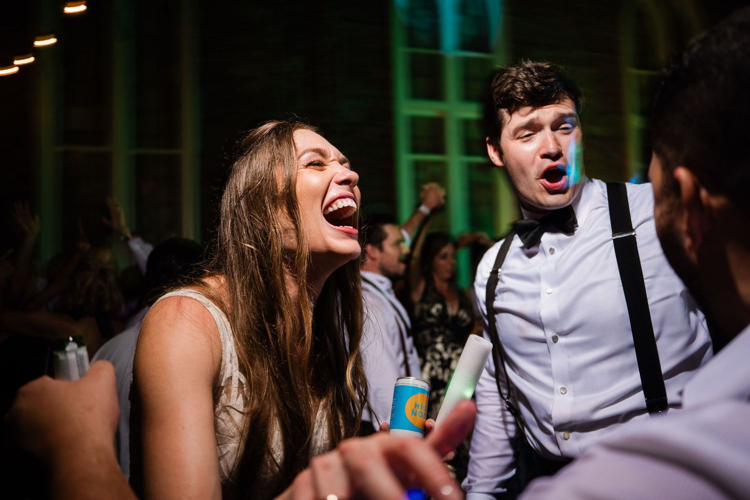 Wedding guests share a joyful moment dancing and laughing together on the dance floor at a reception.