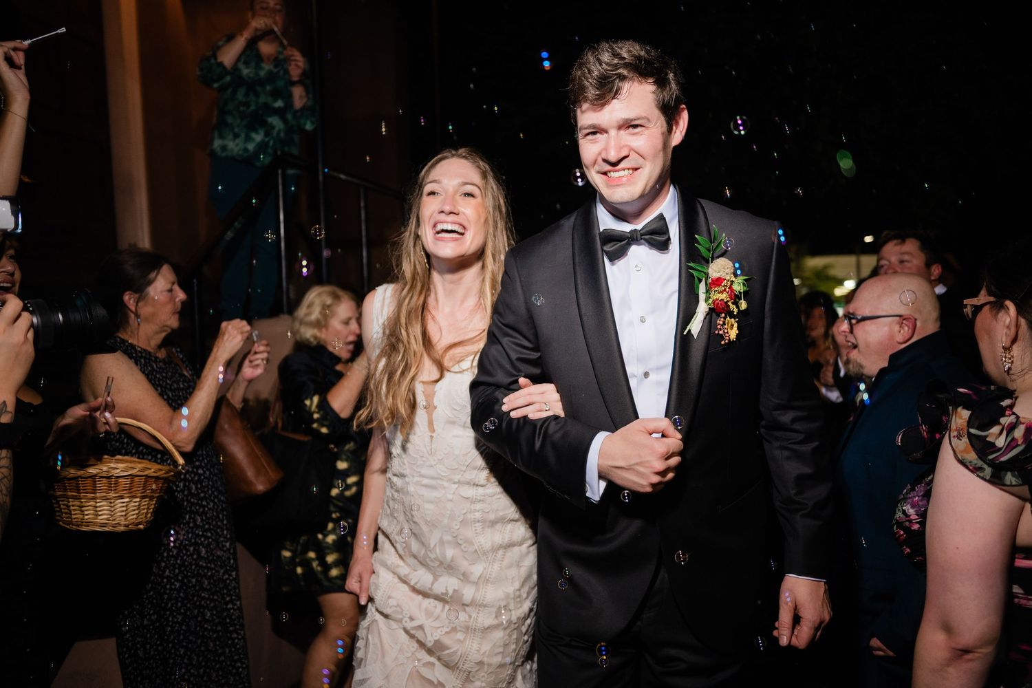 Elegant evening wedding reception with guests dancing in formal attire under ambient lighting.