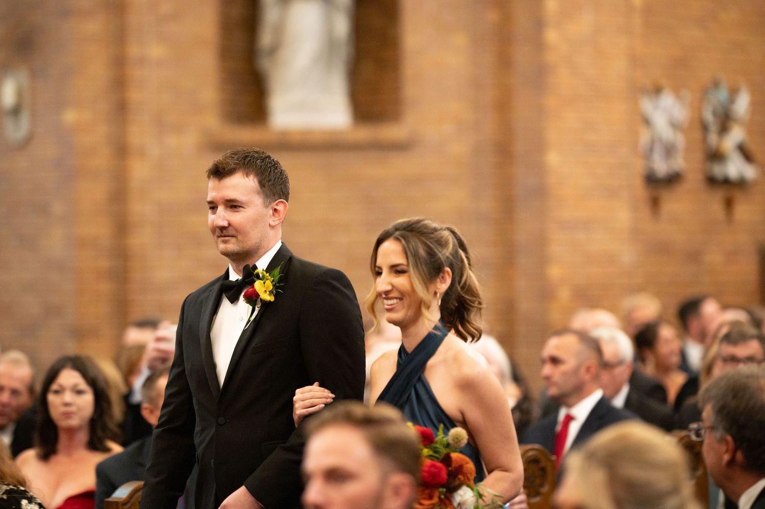 Wedding guests celebrating in a rustic brick-walled venue with arched details.