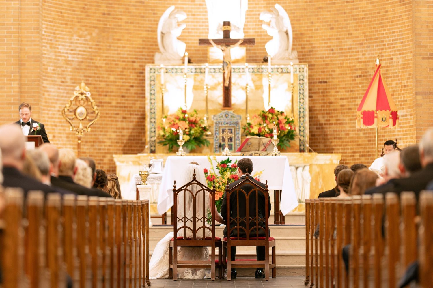 Interior of traditional brick church with ornate altar and warm lighting for wedding ceremony.