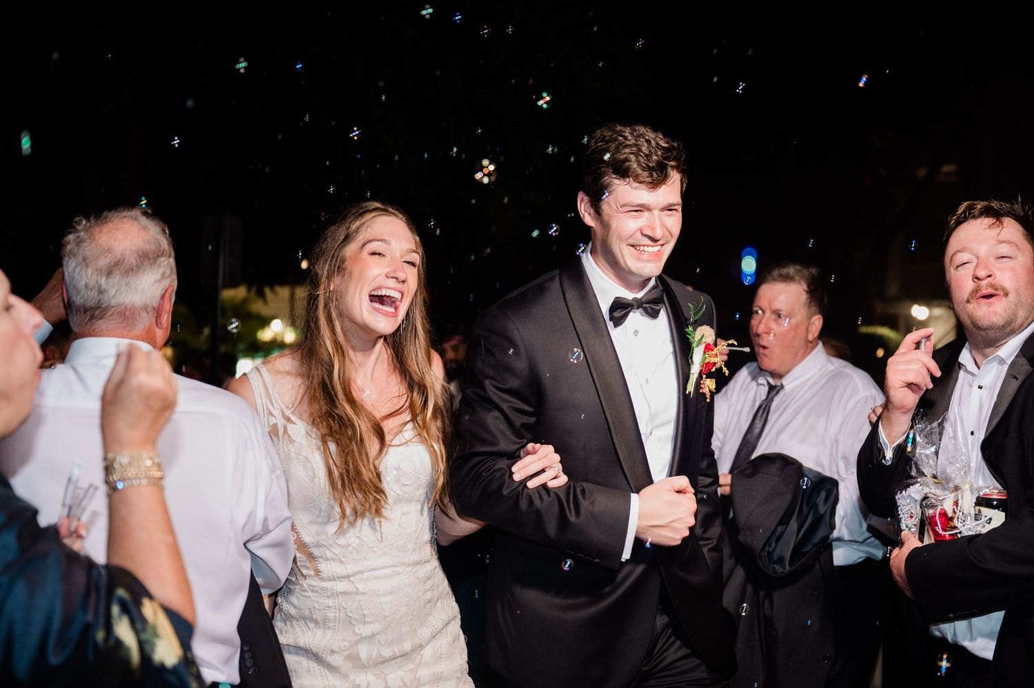 Wedding reception guests celebrating and dancing together in a dimly lit venue.